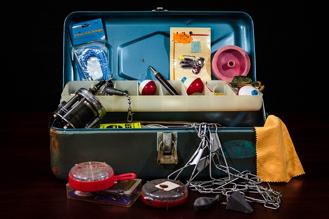 Old fashioned metal tackle box. Tackle includes red and white bobbers, fishing hooks, rubber lures, metal fish stringer.